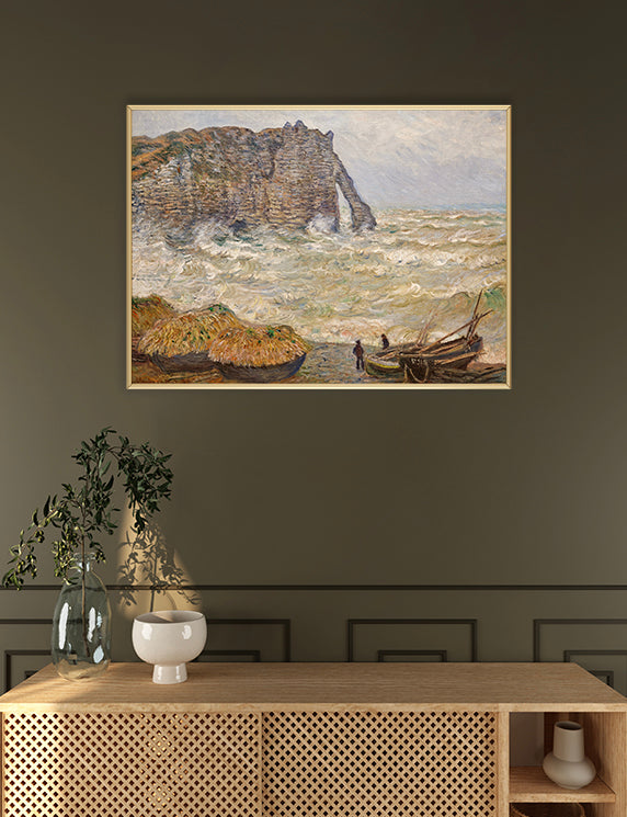 Framed painting of a coastal scene with boats and cliffs on a wall above a wooden console table.