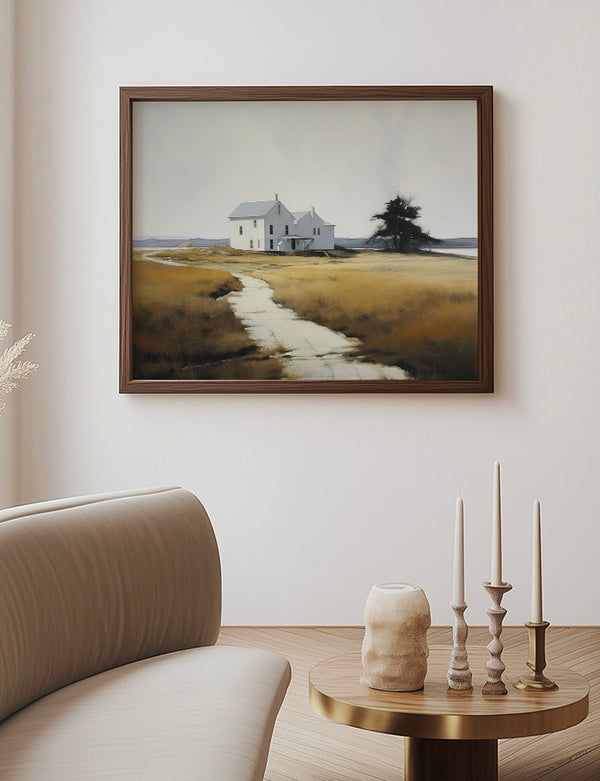 Framed artwork of a house in a field on a wall above a sofa and side table.