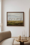 Framed artwork of a landscape with a field and clothesline on a wall above a sofa.