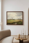 Framed landscape painting on a wall above a sofa in a living room.