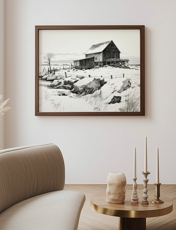 Framed black and white landscape print of a snowy scene with a wooden cabin on a wall above a sofa.