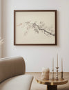 Framed artwork of a branch on a wall above a sofa and side table with decorative items.