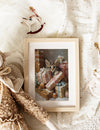 Framed picture of a kitten among Christmas presents on a soft surface with toys.