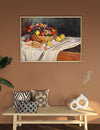 Framed still life painting on a wall above a wooden bench with decorative pillows and vases.