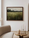 Framed landscape print on a wall above a table with decorative items in a room.