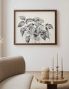 Framed botanical artwork on a wall above a sofa and side table with decorative items.