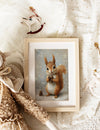Framed picture of a squirrel on a soft, textured surface with decorative elements.