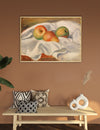 Framed painting of apples on a white cloth above a wooden bench with decorative pillows and vases.