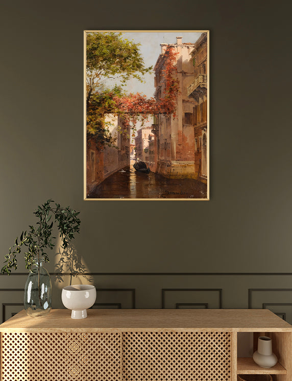 Framed artwork of a canal scene on a wall above a wooden console table.