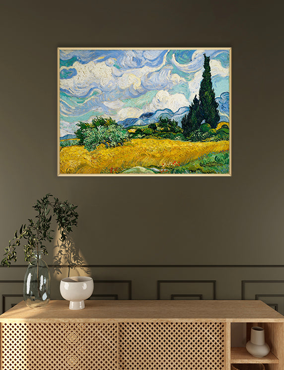Framed Van Gogh painting of a landscape with a cypress tree on a wall above a wooden console table.